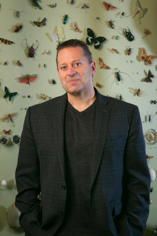 Jason Cryan stands before a museum display of insects. 
