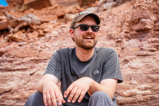Randy Irmis smiles while sitting in the desert. 