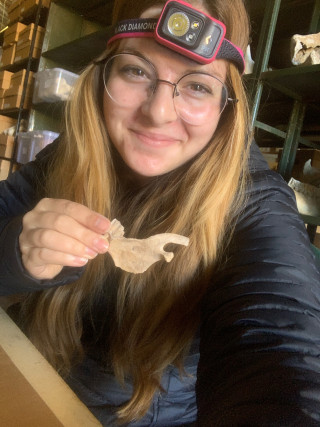 Kathryn holds a fossil and smiles.