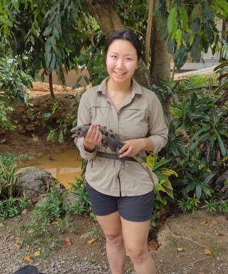 Claudia smiles at the camera holding a lizard.