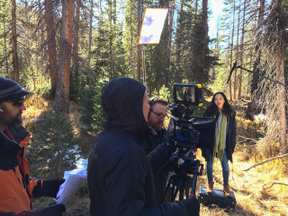 This is an image of a woman being filmed in the woods.