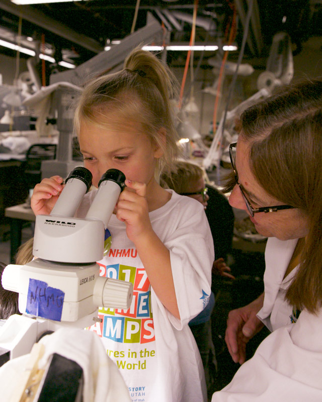 A girl peers into a microscope.