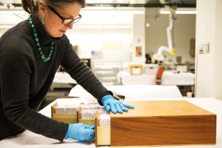 An anthropologist opens a drawer of lantern slides in a museum&#039;s lab. 