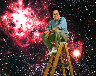 A man sits on a ladder in front of a backdrop of a galaxy.