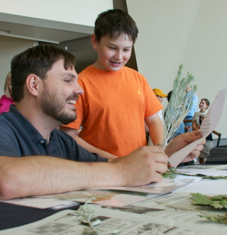 A museum staff member helps kids at an event.