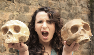 Ella holds two human skulls.