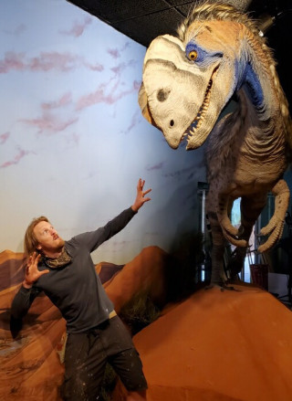 Paleoartist Brian Engh next to a dinosaur sculpture. 