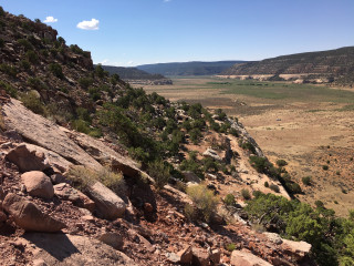 A view from the Dystrophaeus Quarry, showing the orange bands of the canyon and scrubby valley floor below.