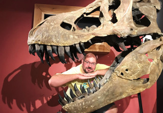 Casey poses inside the mouth of a T-rex fossil skull.