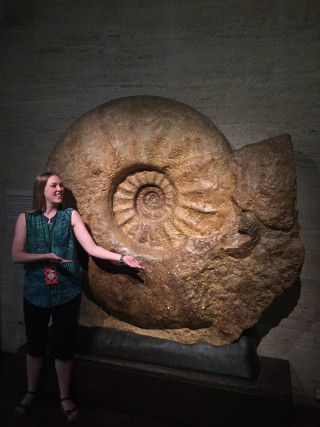 Dr. Kathleen Ritterbush next to a massive ammonite fossil.