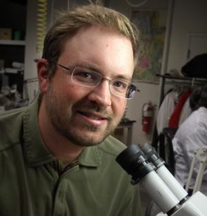 A paleontologist next to a microscope. 