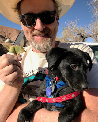 John in the field holding his dog.