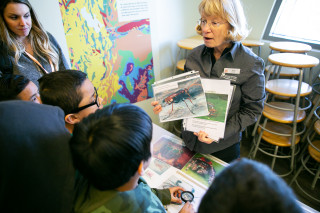 NHMU Volunteer Jane Yager works with a group of field trip students at the Museum.