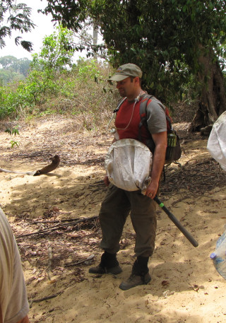 Jason holds an insect catching net in a jungle.