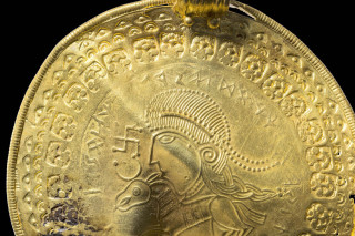 A golden bracteate inscribed with runes. 