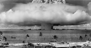 A mushroom cloud from a nuclear weapon test over the ocean.