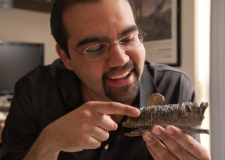 Dr. Ali Nabavizadeh smiles while pointing at a fossil.