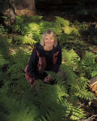 Suzanne Simard smiles surrounded by foliage.