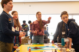 Kids work on a project around a table. 