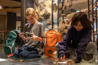 Children sit in a gallery at NHMU using contents of a sensory bag.