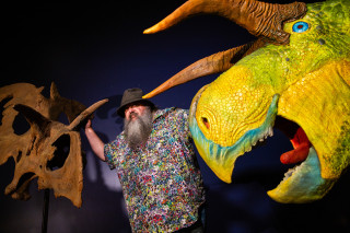 Mark Loewen stands next to casts of the head of the dinosaur Lokiceratops. 