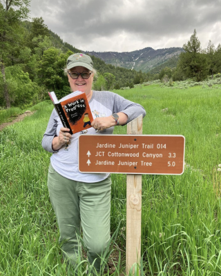 Lisa Morey stands next to a sign post on a hiking trail.