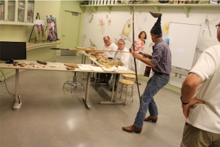 A man demonstrates indigenous tools in front of a small audience