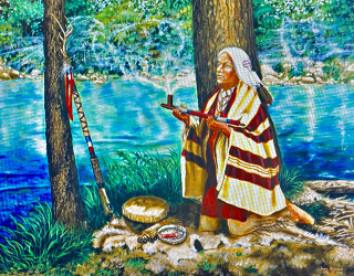 A painting of an Indigenous man kneeling by water with a smoking pipe in his hands. 