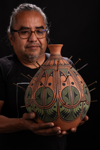 Artist Rowan Harrison holds one of his pots. 