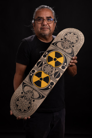 Artist Rowan Harrison holds his hand-painted skateboard. 