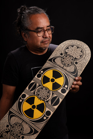 Artist Rowan Harrison holds his hand-painted skateboard. 