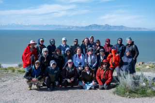 A group of teachers in coats in a group photo in front of the Great Salt Lake