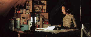 Dr. Jane Goodall sitting at her desk in her tent in the Gombe National Forest