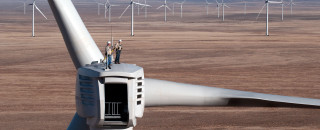 Maintenance workers stand at the top of a wind turbine. 