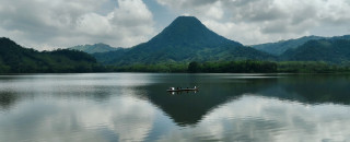 A canoe of people on a lake with a volcano in the background. 