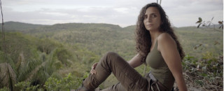 Ella Al-Shamahi sit on a rock ledge in the jungle.