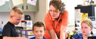 An instructor works with kids in a classroom.