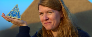 Sarah sits outside a pyramid