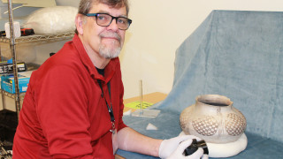 NHMU Volunteer Mark Marzolf photographs artifacts in the anthropology collections. 