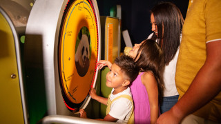 A family plays on a scale in the exhibit. 