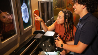 A young couple play with an interactive in the exhibit that mimics an Xray machine.