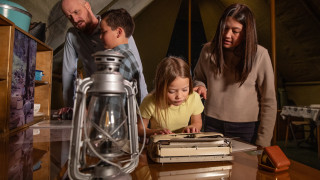 A family looks at objects inside a mock tent in the Becoming Jane exhibit.