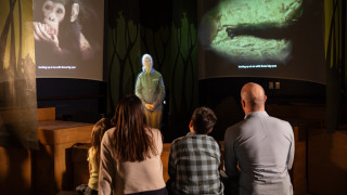 A family listens to a projection of Jane Goodall in the Becoming Jane exhibit. 