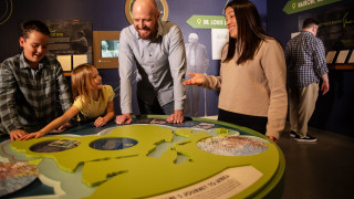 A family looks at a map of Africa in the Becoming Jane exhibit. 