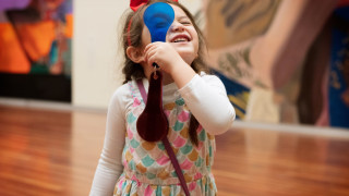 A girl examines art at UMFA using a colored lens issued in a sensory bag.