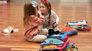 Two girls sit an explore the contents of a sensory bag during a visit to UMFA. 