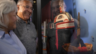 An older couple views an indigenous artifact through a glass case. 