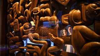 A couple looks at a wood carving in a display case. 