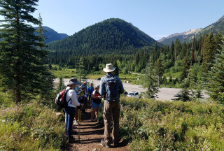 A group of teachers on a trail with wooded mountains in the background
