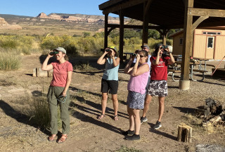 A group of teachers in an outdoor classroom using binoculars